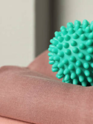 Turquoise dryer ball on brown soft clothing, closeup