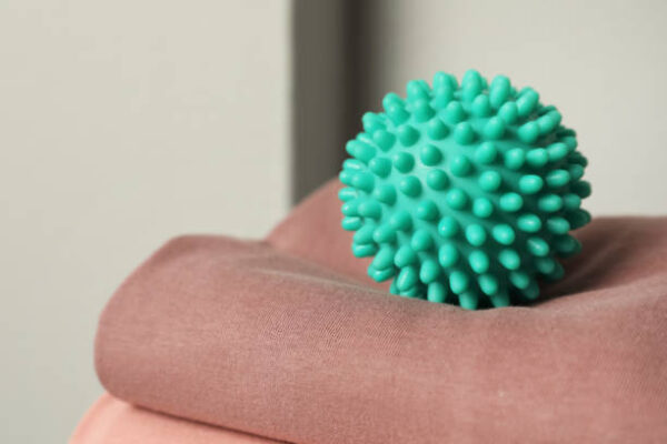 Turquoise dryer ball on brown soft clothing, closeup